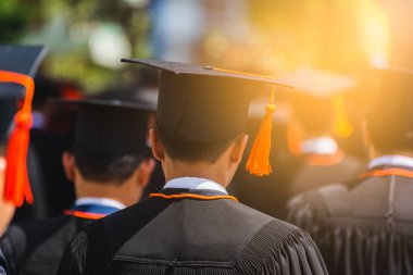 Mezunların arka görünüşü üniversitedeki mezuniyet törenine katılıyor. Üniversite teması konseptinde eğitim mezuniyeti.