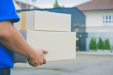 Mavi üniformalı teslimatçı elinde karton kutu tutuyordu..