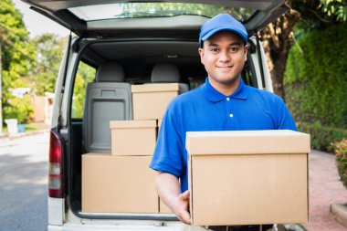 Mavi teslimatçı elinde karton kutu tutuyor..