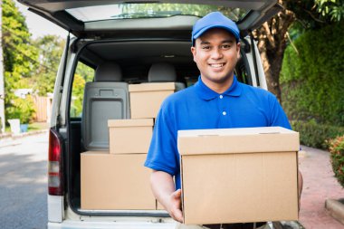 Mavi teslimatçı elinde karton kutu tutuyor..