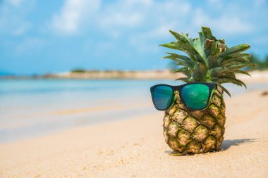 Tropik plaj arka planında güneş gözlüklü ananas. Yaz konsepti