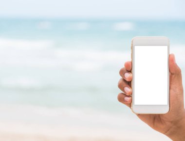 Erkek el, tropik plajda boş akıllı telefon ekranı gösteriyor.