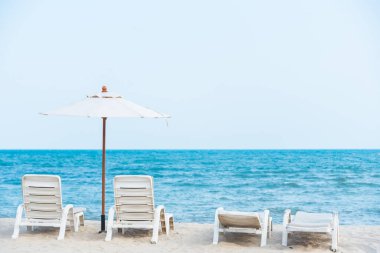 Tropikal plajda beyaz plaj sandalyesi