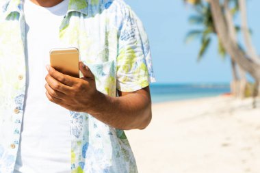 Sahilde akıllı telefon kullanan bir adam..