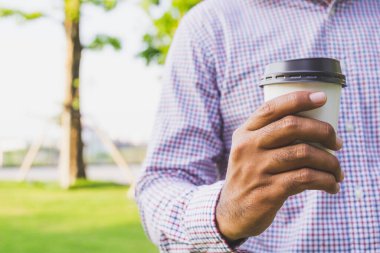 Kapalı kapılar ardında elinde kahve bardağı tutan adam..