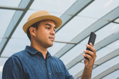 Genç Asyalı adam akıllı telefon kullanıyor..