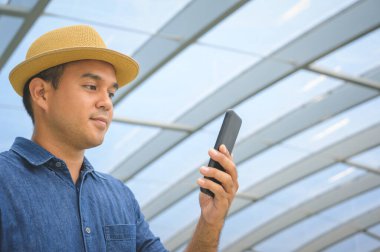 Genç Asyalı adam akıllı telefon kullanıyor..