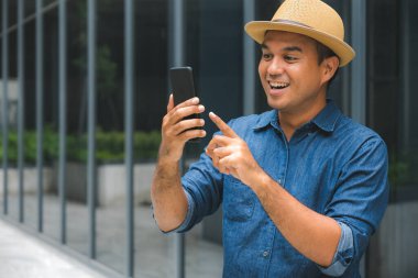 Genç Asyalı adam akıllı telefon kullanıyor..