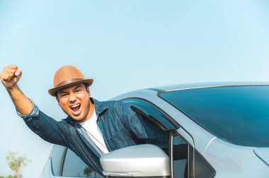 Genç yakışıklı Asyalı adam tatil zamanlarında güzel mavi gökyüzü ile seyahat etmek için araba kullanıyor..