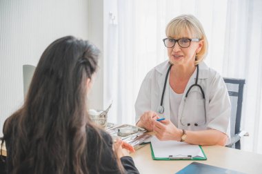 Kıdemli bayan doktor hastayla buluş ve semptom sorunu hakkında görüş ve notlar al. Tıp konseptinde sağlık ve müşteri hizmetleri.