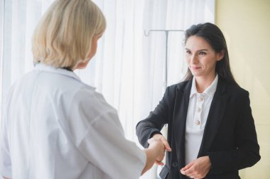 Bayan doktor hastayla tanış ve tokalaş.