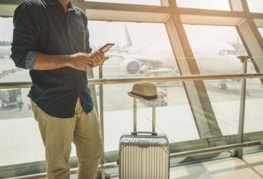 Turistler havaalanındaki akıllı telefonlarından tur programlarını kontrol ediyorlar..