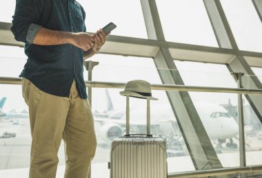 Turistler havaalanındaki akıllı telefonlarından tur programlarını kontrol ediyorlar..
