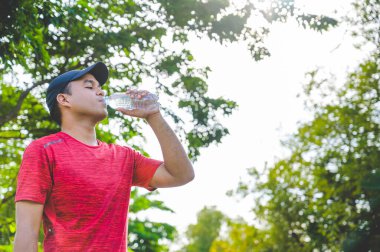 Genç fitness koşucusu bir şişe su içiyor..