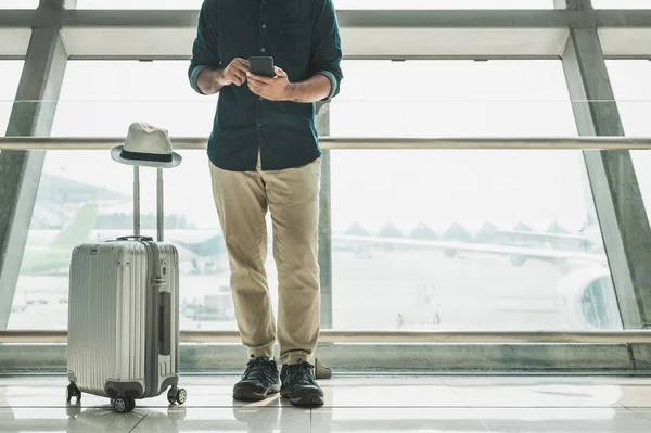 Turistler havaalanındaki akıllı telefonlarından tur programlarını kontrol ediyorlar..