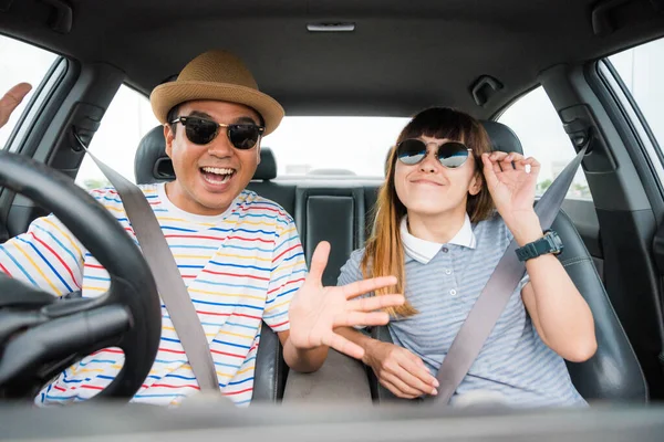 Front view of Funny moment couple asian man and woman sitting in car. Enjoying travel concept.