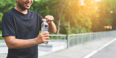 Genç fitness koşucusu bir şişe su içiyor..