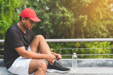 Koşan adam ayakkabı bağcıklarını bağlıyor.