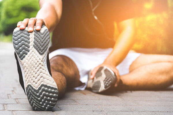 Young man runner stretching for warming up before running or working out