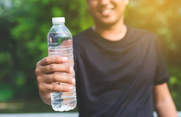 Young fitness man runner  drinking bottle of water.