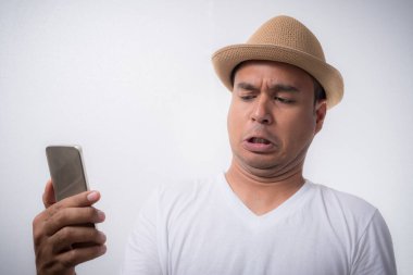 Genç Asyalı adam akıllı telefona bakıyor ve aşırı yüz ifadesiyle şok ve şaşkınlık hissediyor..