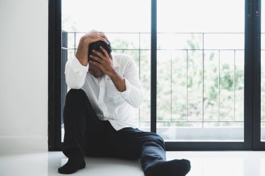 Genç Asyalı adam kafasının içinde karanlık odada oturuyor depresif, yalnız, dramatik ve üzgün.