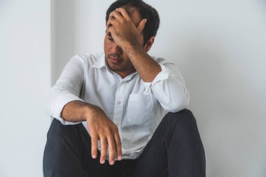 Genç Asyalı adam kafasının içinde karanlık odada oturuyor depresif, yalnız, dramatik ve üzgün.