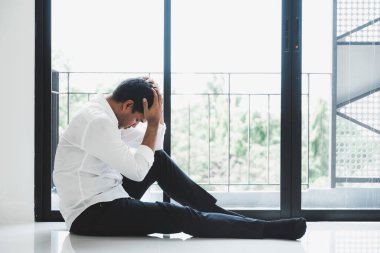 Genç Asyalı adam kafasının içinde karanlık odada oturuyor depresif, yalnız, dramatik ve üzgün.