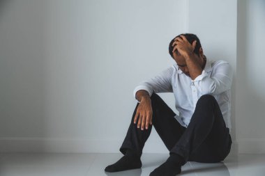 Genç Asyalı adam kafasının içinde karanlık odada oturuyor depresif, yalnız, dramatik ve üzgün.