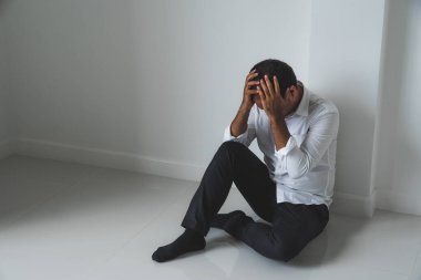 Genç Asyalı adam kafasının içinde karanlık odada oturuyor depresif, yalnız, dramatik ve üzgün.