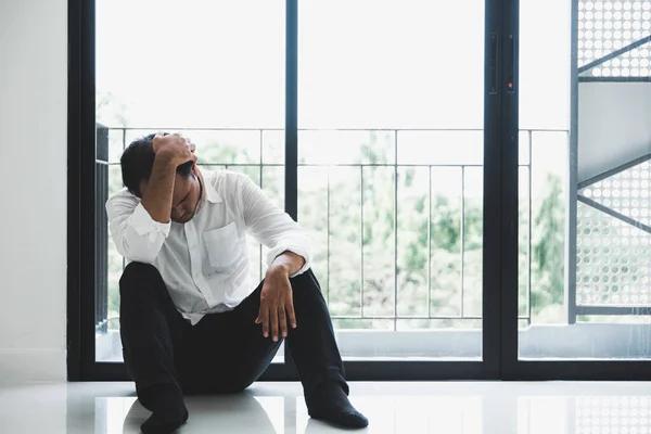 Young asian man sitting in the dark room hand in head feeling depressed, lonely, dramatic and sad.