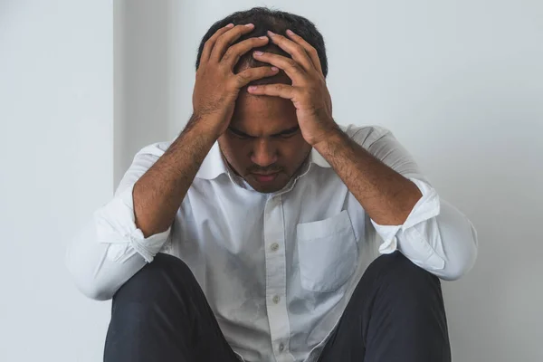 Young asian man sitting in the dark room hand in head feeling depressed, lonely, dramatic and sad.