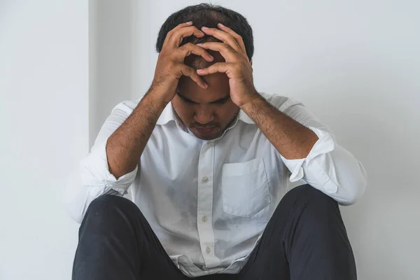 Young asian man sitting in the dark room hand in head feeling depressed, lonely, dramatic and sad.