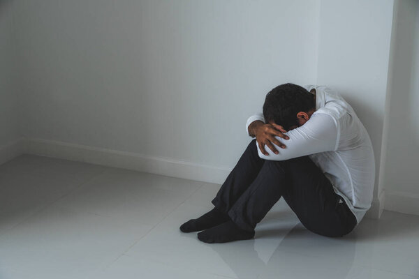 Молодой азиат сидит в темной комнате рука об руку, чувствуя себя подавленным, одиноким, драматичным и грустным
.