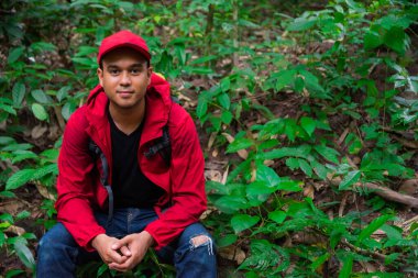 Genç Asyalı ormanda oturuyor..