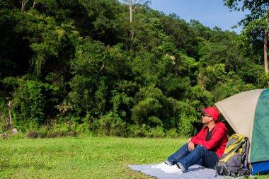 Doğada çadırı olan Asyalı genç bir gezgin. Sırt çantası, Rahatlatıcı, Tatil, Etkinlikler, Kopya alanı ile Yürüyüş kavramı.