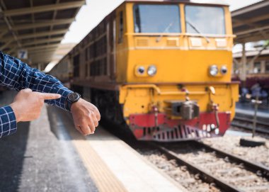 Traveller, Bangkok tren istasyonunda tren beklerken saat arıyor.