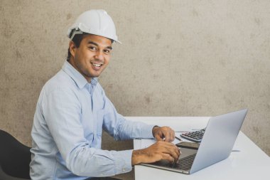 Asyalı inşaat mühendisi dizüstü bilgisayarla planlama projesi yapıyor.