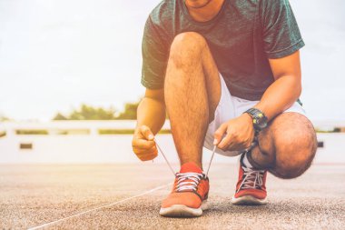 Bağcıklarını bağlayan koşucu genç adam koşu pistinde yarışa hazırlanıyor..