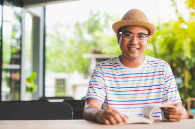 Asyalı genç bir adam kitap okuyor..