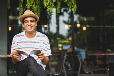 Asyalı genç bir adam kitap okuyor..