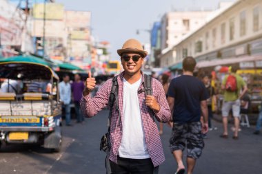 Genç Asyalı gezgin adam Bangkok 'ta Khaosan Yolu' nda yürüyor.