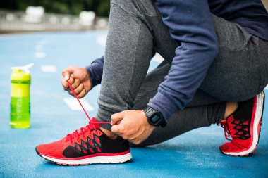 Yaklaş. Koşan adam ayakkabı bağcıklarını bağlıyor.