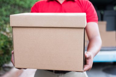 Paket karton kutulu kırmızı üniformalı teslimatçı.