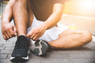 Bağcıklarını bağlayan koşucu genç adam koşu pistinde yarışa hazırlanıyor..