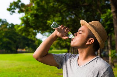 Genç yakışıklı Asyalı adam su içiyor.