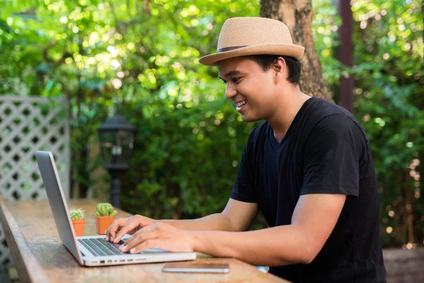 Ung Asiatisk Man Med Hatt Använder Laptop För Sitt Arbete — Stockfoto