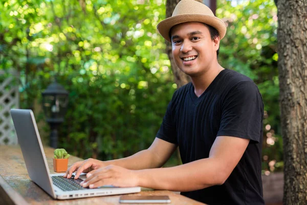 Ung Asiatisk Man Med Hatt Använder Laptop För Sitt Arbete — Stockfoto