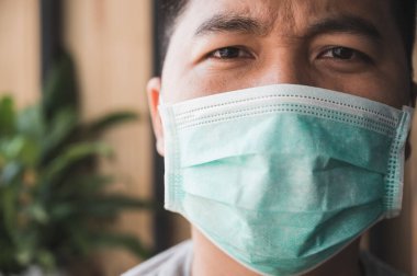 Korunaklı yüz maskesi takan Asyalı genç adamı Coronavirus 'a karşı kapatın..