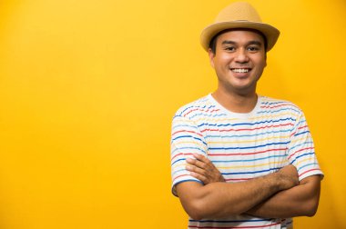 Sarı arka planda kolları çapraz olan yakışıklı Asyalı bir adam..